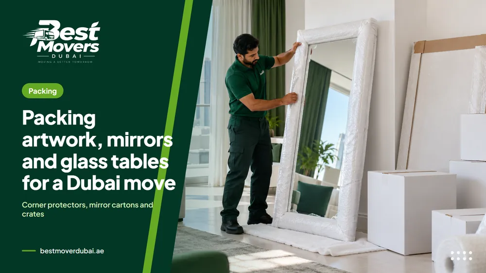A mover wrapping a tall framed mirror in a Dubai apartment living room with white cartons stacked behind him