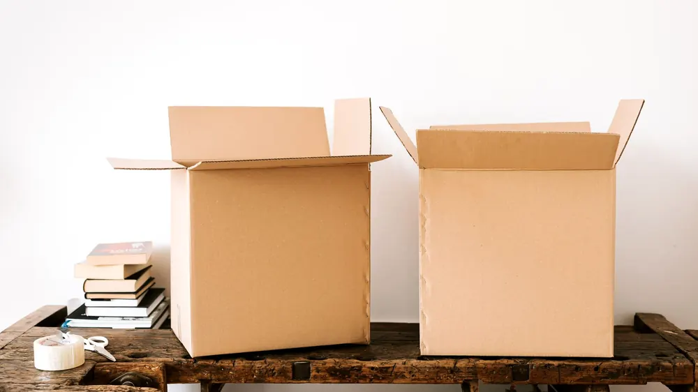 Empty moving boxes and rolls of tape on a living room floor before packing starts